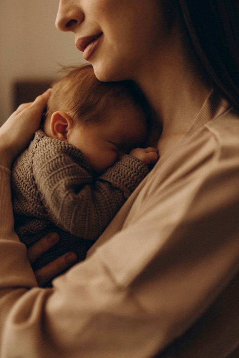 Mother holding swaddled newborn close