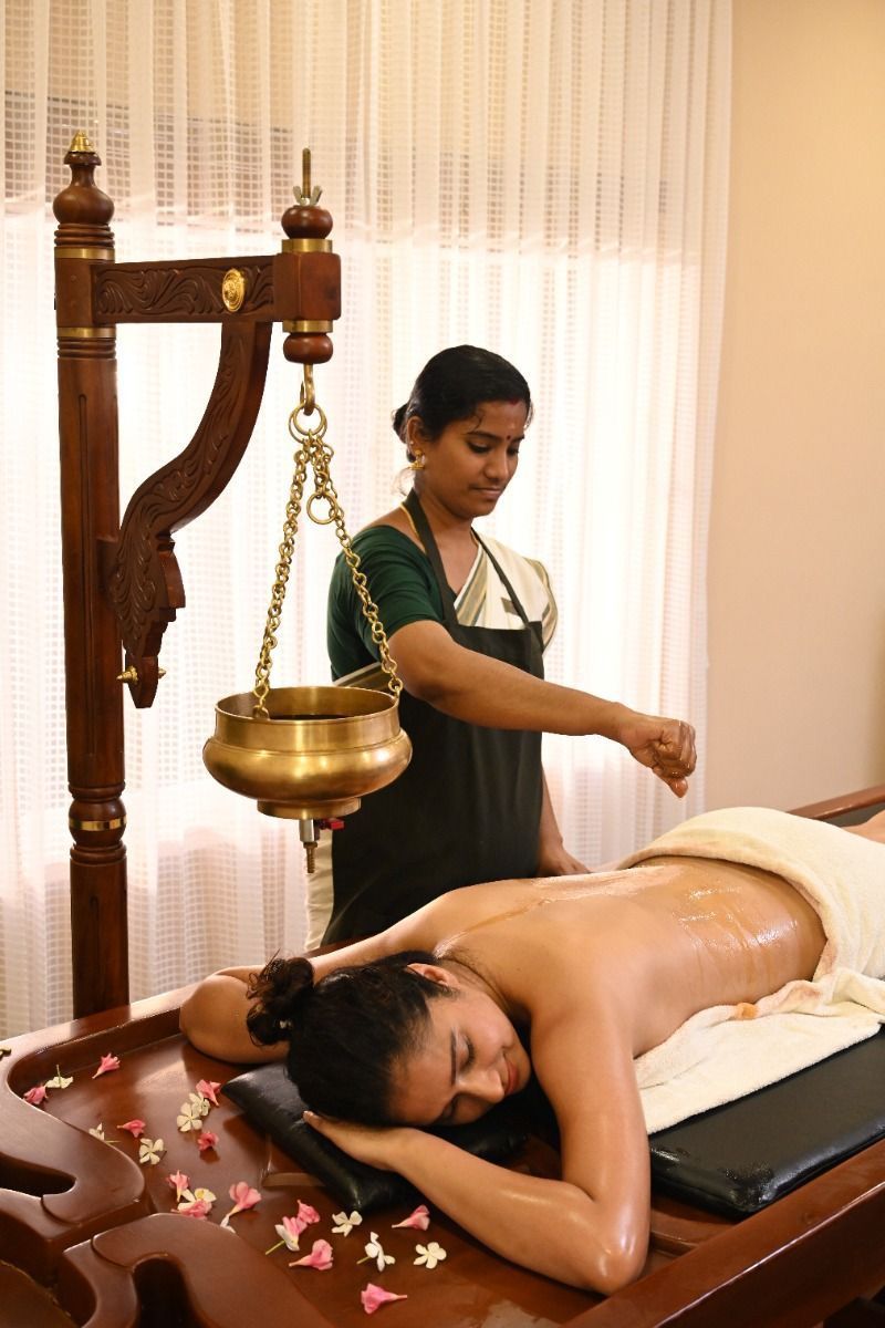 Kerala shirodhara therapy with brass vessel and flower petals